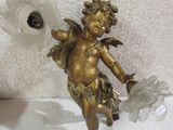 une petite statue représentant un Cupidon tenant une fleur, posée sur une table