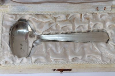 une cuillère en argent et un repose-cuillère dans une boîte