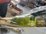 une personne tenant une bouteille de vin emballée dans du plastique