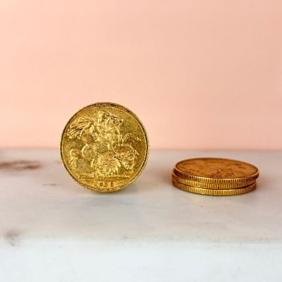 a gold coin sitting next to a stack of gold coins