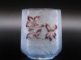 un vase en verre contenant des fleurs, posé sur une surface noire