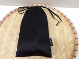 a black bag on a bamboo tray with a pink ribbon