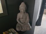 a statue of a person sitting on a shelf next to a book