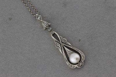 un gros plan d'un collier en argent orné d'une perle