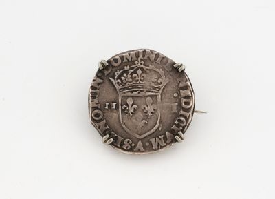 une vieille pièce d'argent sur laquelle figure une couronne, posée sur une surface blanche