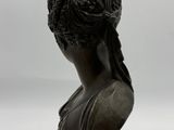a bronze busturine of a woman with long hair