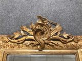 a mirror with a gold frame and a bird on it