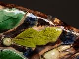 a close up of a decorative vase with leaves on it