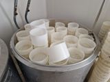 un seau rempli de tasses posé par terre