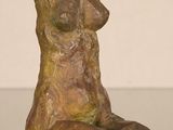 statue of a woman sitting on a table with her hands on her knees
