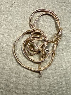a gold necklace with a snake on it on a beige cloth