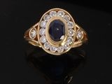 a close up of a gold ring with a sapphire and diamonds