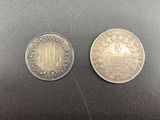 two silver coins sitting on top of each other on a table