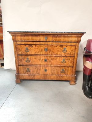 une commode ancienne dans une pièce, à côté d'un fauteuil