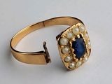 une image représentant une bague en or sertie d'une pierre bleue et entourée de perles