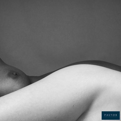 photographie en noir et blanc d'un homme nu allongé sur un lit