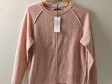 un pull rose suspendu à un cintre accroché au mur