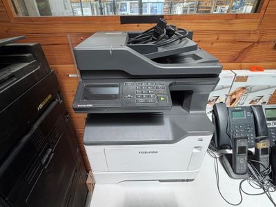 une imprimante posée sur un bureau, à côté d'un téléphone
