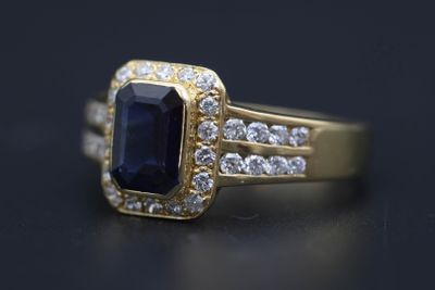 un gros plan d'une bague en or sertie d'une pierre bleue entourée de diamants blancs