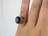 someone is holding a ring with a purple stone on it