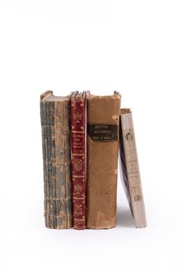 several old books are stacked on top of each other on a white surface