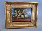 tableau représentant des figues et des feuilles de figuier, dans un cadre doré, posé sur une table