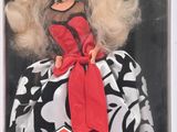 La poupée Barbie porte une robe noire et blanche ornée d'un nœud rouge.