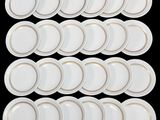 twelve white plates with gold rims on a black background