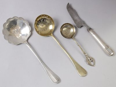 trois cuillères en argent et un couteau posés sur un plan de travail blanc