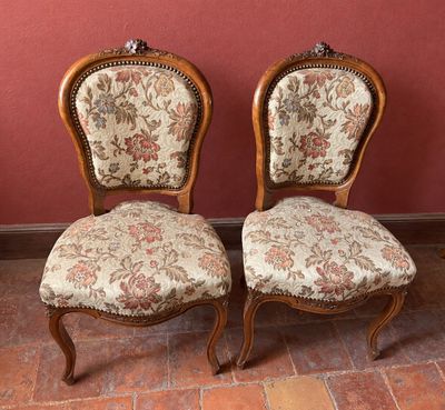 deux chaises aux assises recouvertes d'un tissu à motifs floraux, posées devant un mur rouge