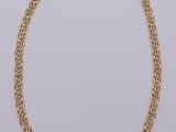 a gold chain necklace with a knot design on a white background