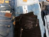 a lot of jeans that are stacked together on a table