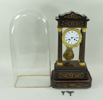 une horloge posée sur la table, sous un dôme en verre