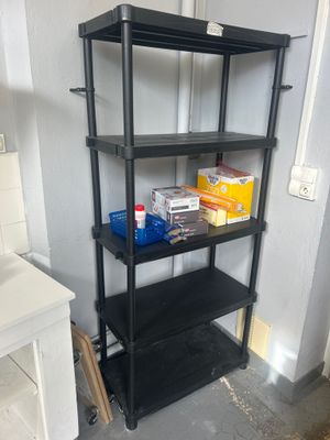 une étagère noire dans un coin de la pièce, à côté d'un lavabo