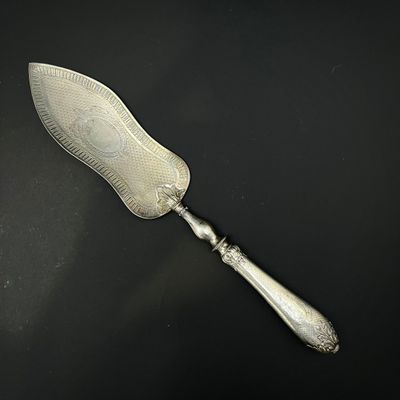 un couteau à beurre ancien plaqué argent posé sur une surface noire