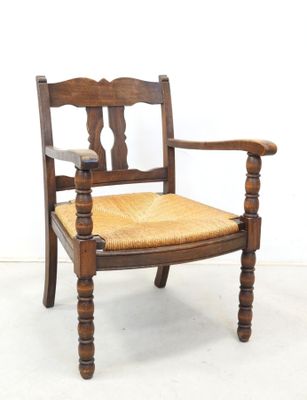 an image of a wooden chair with a woven seat and arm rest