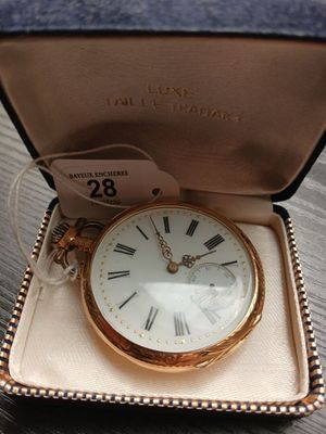 une petite montre de poche en or, dans un écrin posé sur une table