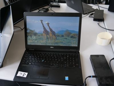 un ordinateur portable posé sur un bureau, à côté d'autres ordinateurs portables