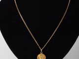un collier avec une pièce d'or sur un mannequin noir