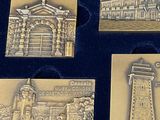 four metal plaques of different types of buildings in a display case