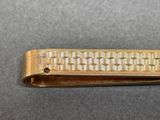 a gold tie bar that has a design on it