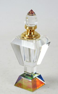 un flacon de parfum en verre transparent muni d'un bouchon doré, posé sur une surface blanche