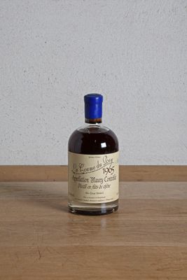 une bouteille d'alcool posée sur une table, avec un mur blanc en arrière-plan