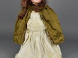 an antique doll of a woman in a white dress and green cape