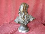 bronze bust of a woman on a pedestal with a red background