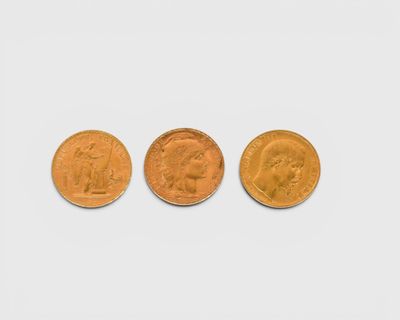 trois types différents de pièces d'or sur une surface blanche