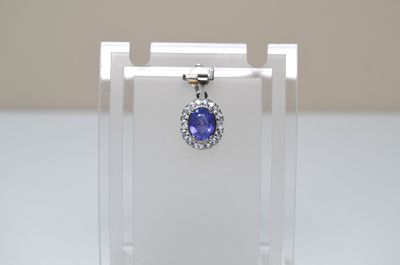 an image of a blue sapphire and diamond pendant on a clear display case
