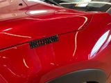 a close up of a red car with a sticker on it ' s hood
