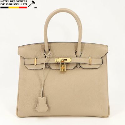 un sac à main en cuir beige muni d'un fermoir doré sur la poignée
