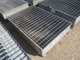 plusieurs grilles en acier sont empilées les unes sur les autres au sol